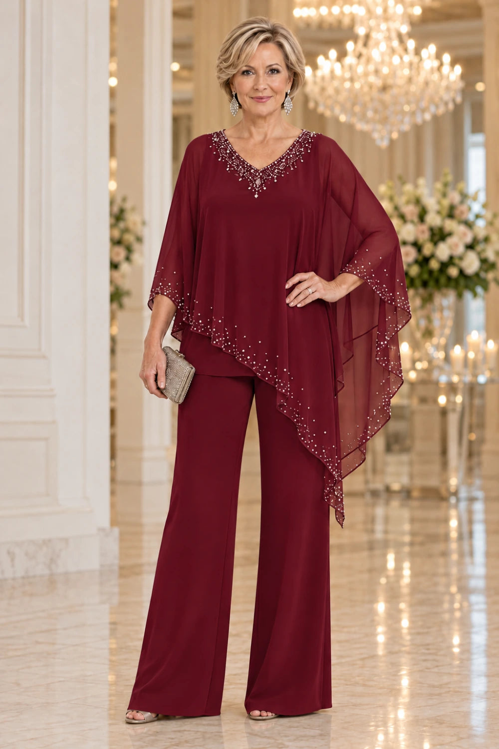 Burgundy trouser outfit with a beaded V neckline and diagonal sheer cape, front view.