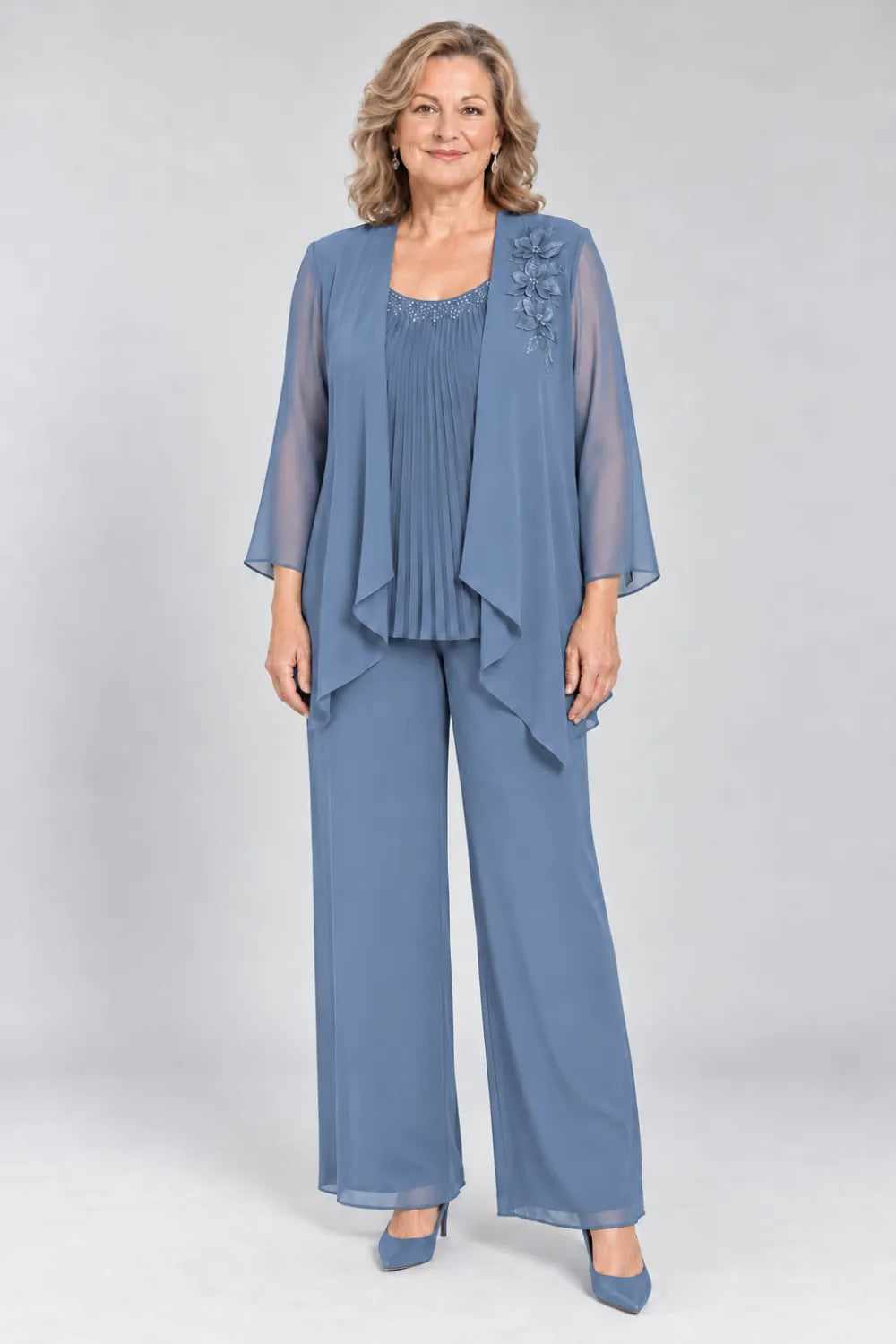 Dusty Blue pant suit with fine pleats, decorated neckline and floral shoulder motif, front view.