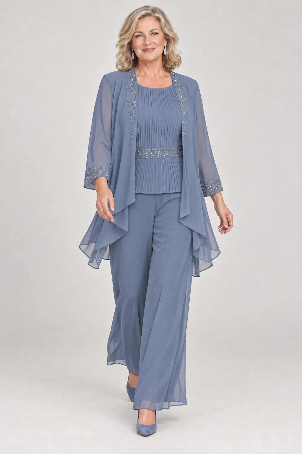 Dusty Blue pant suit with pleated top and beaded waist, jacket edges and cuffs, posed front view.