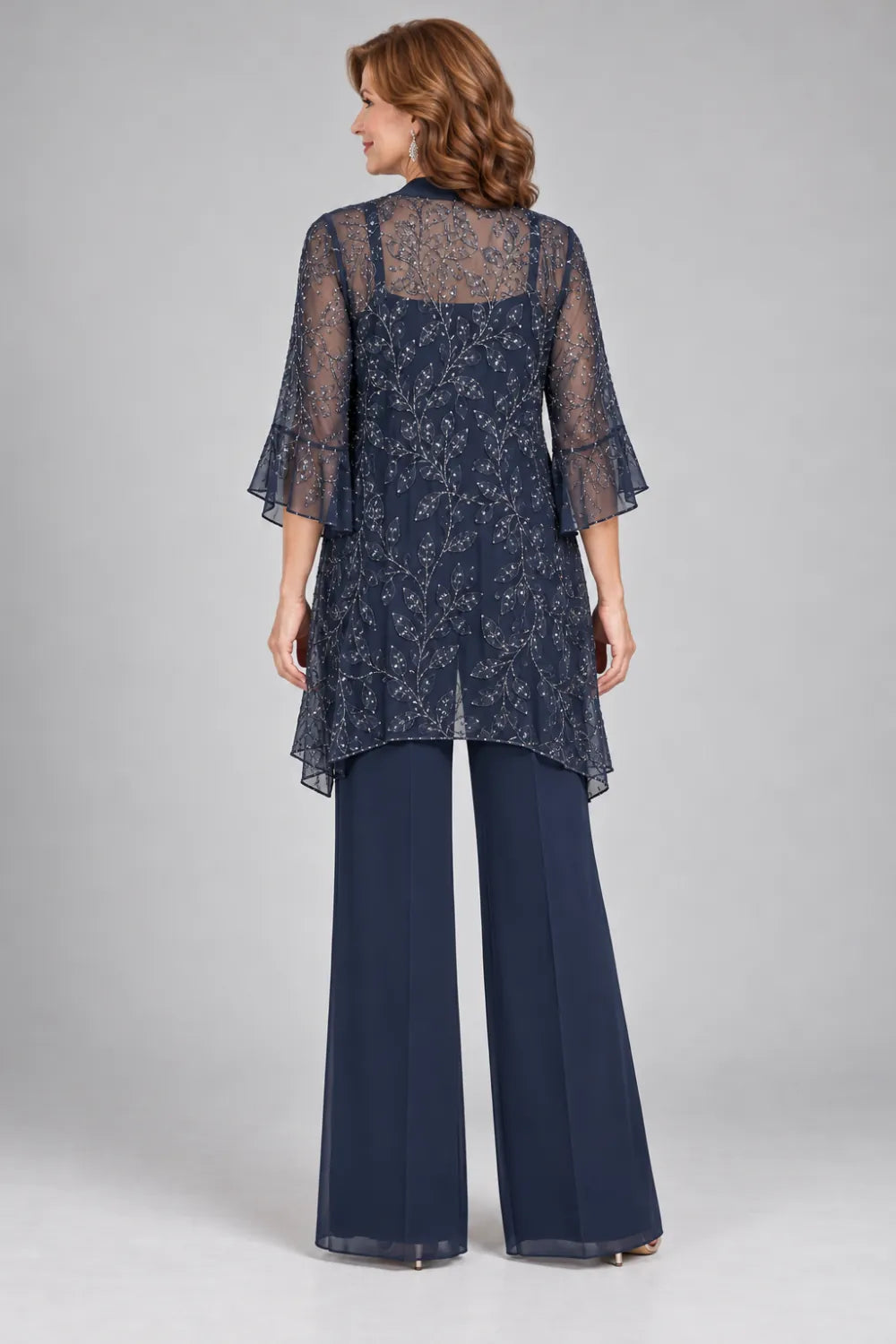 Back view of a navy blue wide-leg pant suit with longline open lace jacket with flared cuffs.
