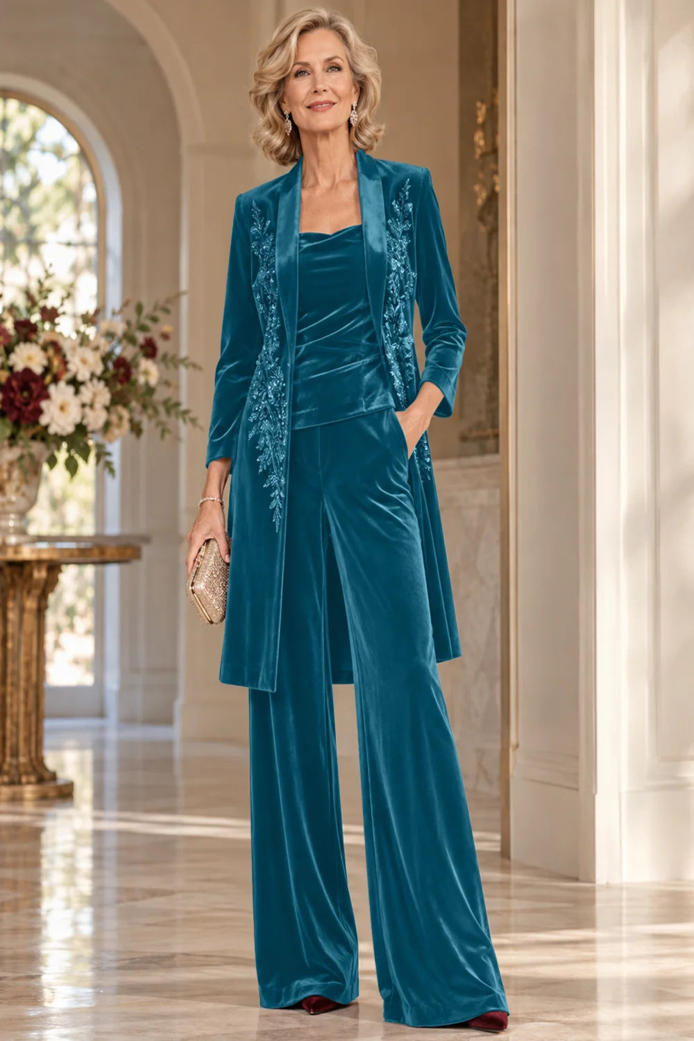 Front view of a teal pant suit with a floral-trimmed long jacket and wide-leg trousers.