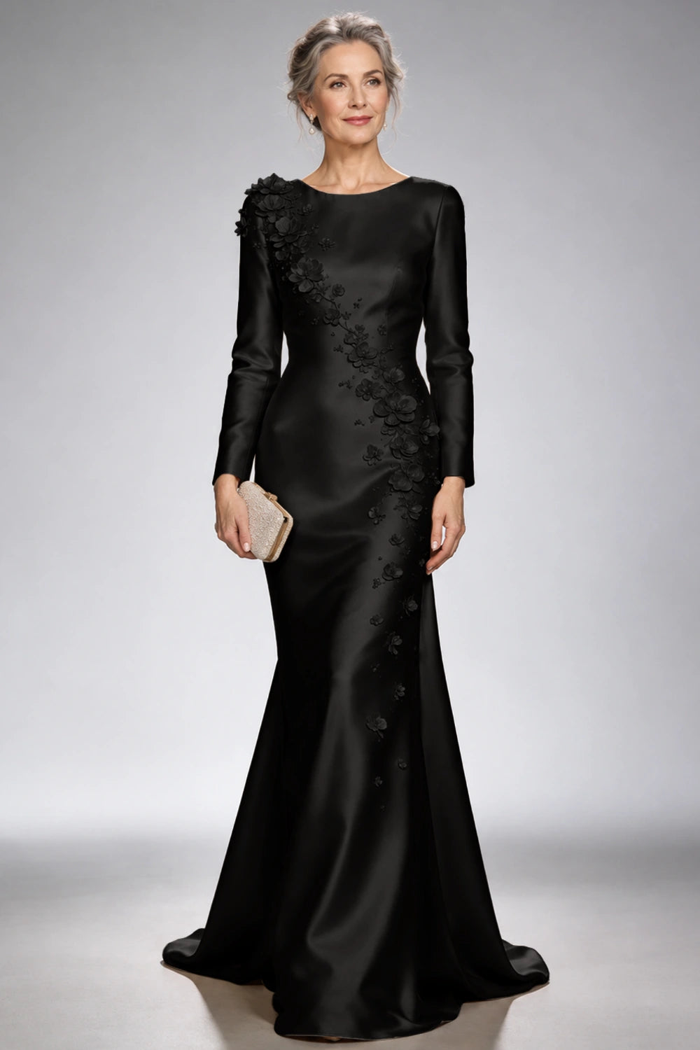 Front view of the black satin mermaid dress with long sleeves and diagonal floral appliques across the bodice and skirt.